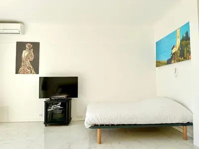 a white room with a bed and a flat screen tv at Alexendre 3 Elégant Studio Centre Cannes proche Palais des festivals in Cannes