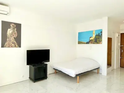 a white room with a bed and a flat screen tv at Alexendre 3 Elégant Studio Centre Cannes proche Palais des festivals in Cannes