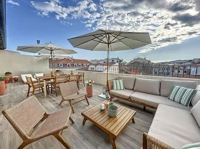 a patio with a couch and tables and umbrellas at 79m2 Penthouse, Palais et plages à 400m rooftop in Cannes