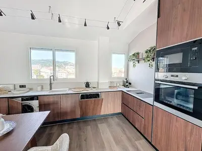 a large kitchen with wooden cabinets and a table at 79m2 Penthouse, Palais et plages à 400m rooftop in Cannes