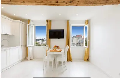 a white dining room with a table and chairs and windows at Palais des Festival view in Cannes