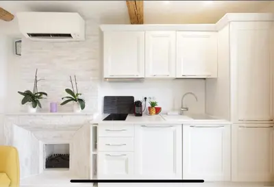 a kitchen with white cabinets and a fireplace at Palais des Festival view in Cannes