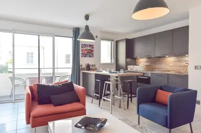 a living room with two chairs and a kitchen at Modern apartment with swimming pool in Cannes