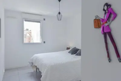 a white bedroom with a white bed and a window at Modern apartment with swimming pool in Cannes
