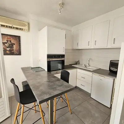 a kitchen with white cabinets and a table and chairs at Studio Cannes le Val D'or Chez Lisa in Cannes