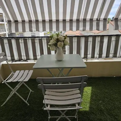 a table and chairs on a balcony with a vase of flowers at Studio Cannes le Val D'or Chez Lisa in Cannes