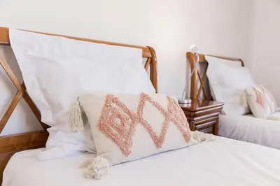 a bed with white and pink pillows on it at Couronne de Joséphine - 10 mn à pied du Palais et plages, charme et authenticité in Cannes