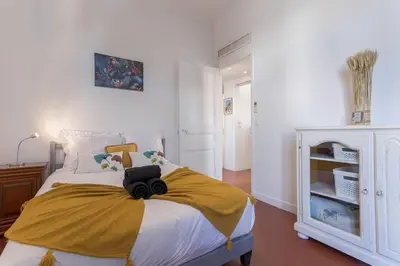 a bedroom with a bed with a yellow blanket on it at Couronne de Joséphine - 10 mn à pied du Palais et plages, charme et authenticité in Cannes
