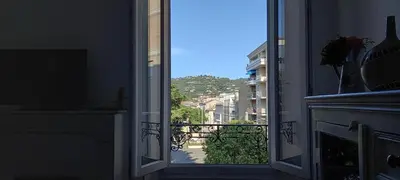 an open door to a balcony with a view of a city at Couronne de Joséphine - 10 mn à pied du Palais et plages, charme et authenticité in Cannes