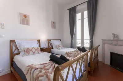 two twin beds in a room with a fireplace at Couronne de Joséphine - 10 mn à pied du Palais et plages, charme et authenticité in Cannes