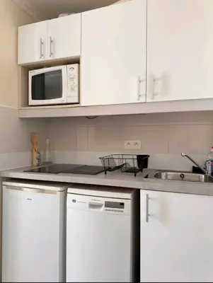 a kitchen with white cabinets and a microwave at Cannes appartement vue mer , piscine in Cannes