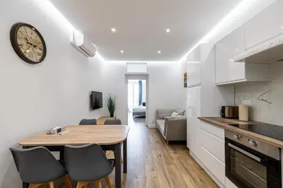 a kitchen and dining room with a clock on the wall at LE BAMBOO idéalement situé en centre-ville, pour familles ou petits groupes in Cannes