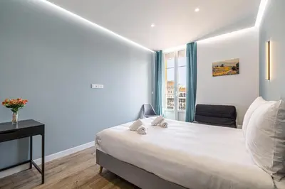 a bedroom with a bed and a desk and a window at LE BAMBOO idéalement situé en centre-ville, pour familles ou petits groupes in Cannes