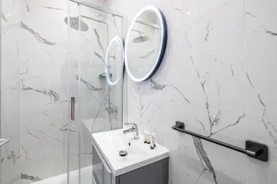 a white bathroom with a sink and a mirror at LE BAMBOO idéalement situé en centre-ville, pour familles ou petits groupes in Cannes