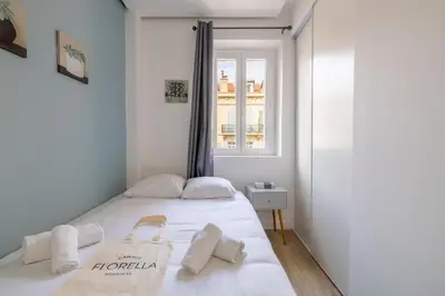 a white bed in a room with a window at LE BAMBOO idéalement situé en centre-ville, pour familles ou petits groupes in Cannes