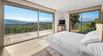 a bedroom with a bed and large glass windows at Villa CANNES in Cannes
