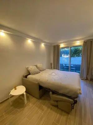 a bedroom with a bed and a table and a window at Appartement neuf Pointe Croisette, 50 m de la mer in Cannes