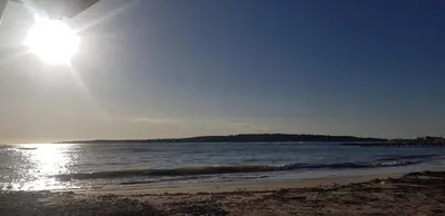 a beach with the sun shining on the water at Appartement neuf Pointe Croisette, 50 m de la mer in Cannes