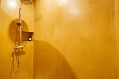 a bathroom with a shower with a yellow wall at Le Bonheur - 5mins Palais des Festivals in Cannes