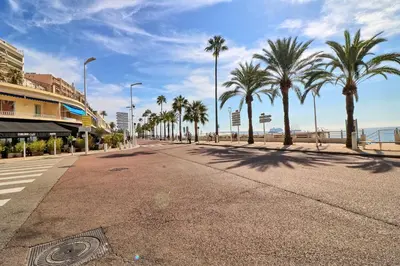 an empty street with palm trees and the beach at Appartement proche des Plages et du Palais in Cannes