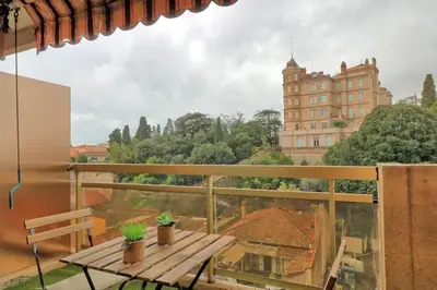 a balcony with a wooden bench and a building at Appartement proche des Plages et du Palais in Cannes