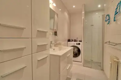 a white bathroom with a sink and a washing machine at Appartement proche des Plages et du Palais in Cannes