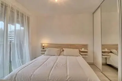 a white bedroom with a large bed and a window at Appartement proche des Plages et du Palais in Cannes