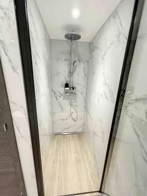 a bathroom with a shower with white marble walls at BRP Cannes Center,Two-Bed Deluxe Apart with Spa bath in Cannes