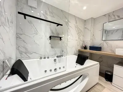 a white bath tub in a bathroom with marble walls at BRP Cannes Center,Two-Bed Deluxe Apart with Spa bath in Cannes