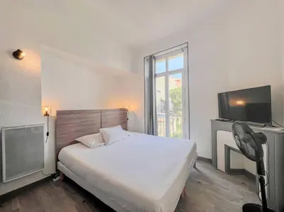 a bedroom with a large bed and a television at Cannes - Charming central apartment with balcony in Cannes