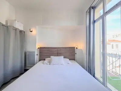 a white bed in a room with a large window at Cannes - Charming central apartment with balcony in Cannes