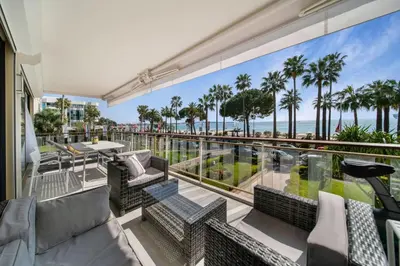 a balcony with a view of the ocean and palm trees at REF 1337 - Cannes Croisette - Sea view apartment for rent in Cannes