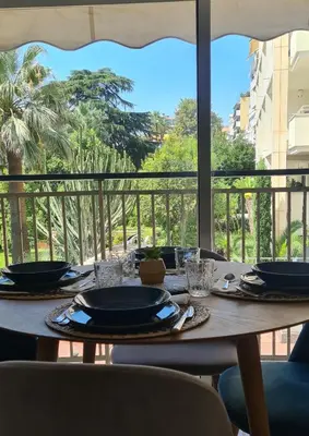 a wooden table with plates and glasses on a balcony at Le Ptit Ecrin du Lerins in Cannes