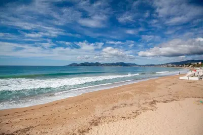 a beach with people and the ocean on a cloudy day at Brand New Central Cannes Apt 2 min walk to Palais in Cannes