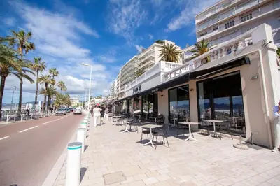 a sidewalk with tables and chairs on a city street at Brand New Central Cannes Apt 2 min walk to Palais in Cannes