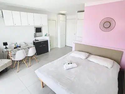 a bedroom with a white bed and a pink wall at Lovely, modern studio with sea view 117 in Cannes