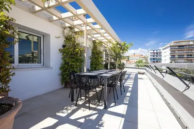 a patio with a black table and chairs on a balcony at Outstanding Rooftop Cannes 4 bed Apt Sea Views in Cannes