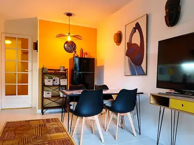 a living room with a table and chairs and a television at CANNES Appartement - terrasse, jardin prive, parking, piscine, climatisation in Cannes