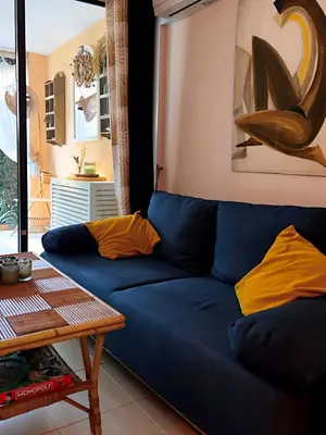 a blue couch with yellow pillows in a living room at CANNES Appartement - terrasse, jardin prive, parking, piscine, climatisation in Cannes