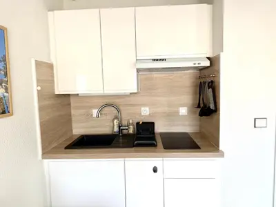 a kitchen with white cabinets and a sink at T2 avec terrasse, Gare Cannes & Croisette à pied in Cannes