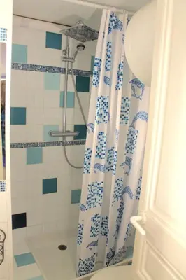 a bathroom with a shower with a blue and white shower curtain at CANNES CENTRE CHARMANT 2 ROOMS+MEZZANIN in Cannes