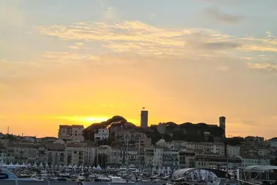 a sunset over a city with boats in a harbor at CANNES CENTRE CHARMANT 2 ROOMS+MEZZANIN in Cannes