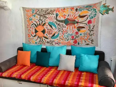 a couch with colorful pillows and a painting on the wall at CANNES CENTRE CHARMANT 2 ROOMS+MEZZANIN in Cannes