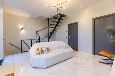 a white couch in a living room with a spiral staircase at Bliss Triplex - Hyper Centre - Sauna - BBQ - Jacuzzi - LRACANNES in Cannes