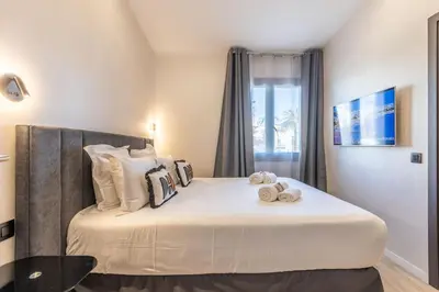 a bedroom with a large white bed with pillows at Bliss Triplex - Hyper Centre - Sauna - BBQ - Jacuzzi - LRACANNES in Cannes