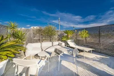a patio with white chairs and tables and a fence at Rooftop la Croisette in Cannes