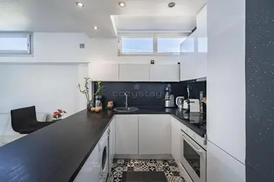 a kitchen with white cabinets and black countertops at Rooftop la Croisette in Cannes