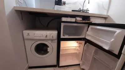 a small kitchen with an open refrigerator and a washer at Winter Palace Beauséjour in Cannes