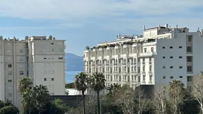 two white buildings and palm trees in front of the ocean at A083 - Modern & Bright apt - Cannes center in Cannes