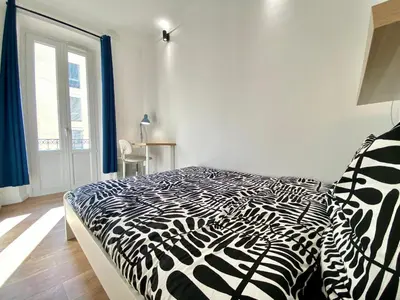 a black and white bed in a room with a window at Volupté By SCLS Locations in Cannes